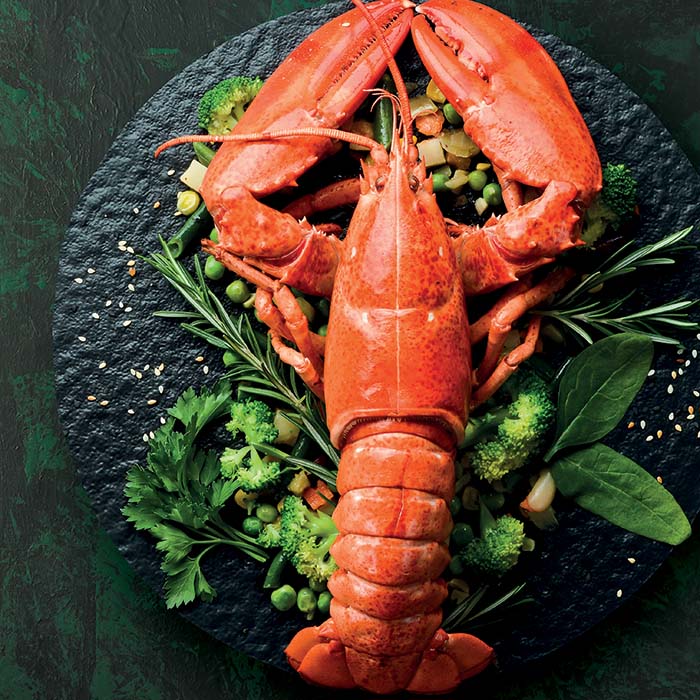 Homards cuits à la perfection, leur carapace rouge éclatante et leur chair tendre, prêts à être dégustés avec des accompagnements savoureux.