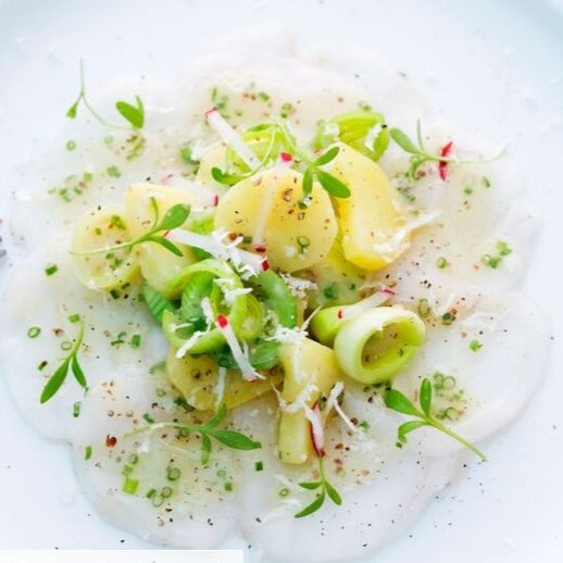 Le carpaccio de lotte est un plat délicat et raffiné, idéal pour les amateurs de fruits de mer. La lotte, avec sa chair blanche et ferme, est tranchée finement et marinée dans un mélange d'huile d'olive, de jus de citron, et d'herbes fraîches comme le persil ou la coriandre. Ce plat est souvent agrémenté de touches de sel de mer et de poivre fraîchement moulu pour rehausser les saveurs naturelles du poisson. Servi en entrée, le carpaccio de lotte est généralement accompagné de fines tranches de pain grillé ou de salade verte pour une expérience gustative légère et savoureuse.