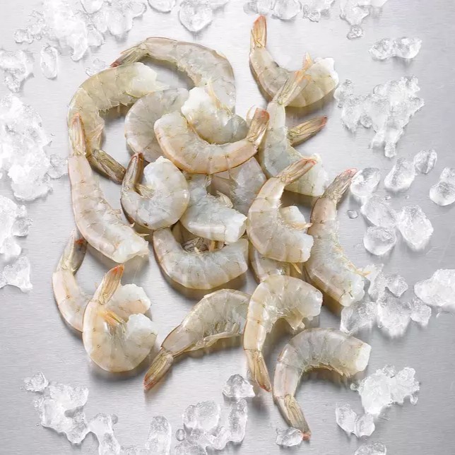 Crevettes cocktail servies avec leur queue, présentées élégamment sur un lit de salade fraîche, accompagnées d'une sauce cocktail onctueuse.